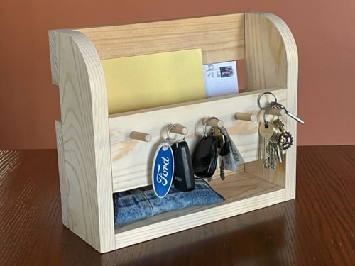 Wooden key rack with 5 pegs with keys hanging on them and mail slot